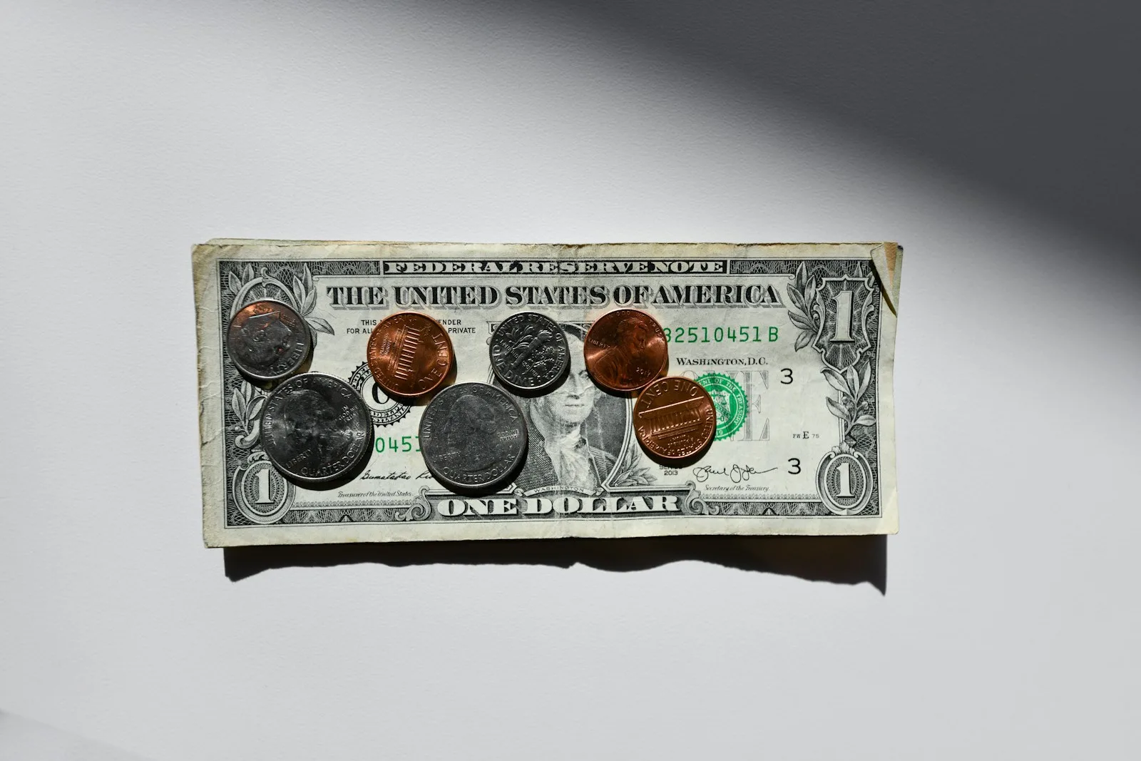 A one dollar bill with coins placed on top of it