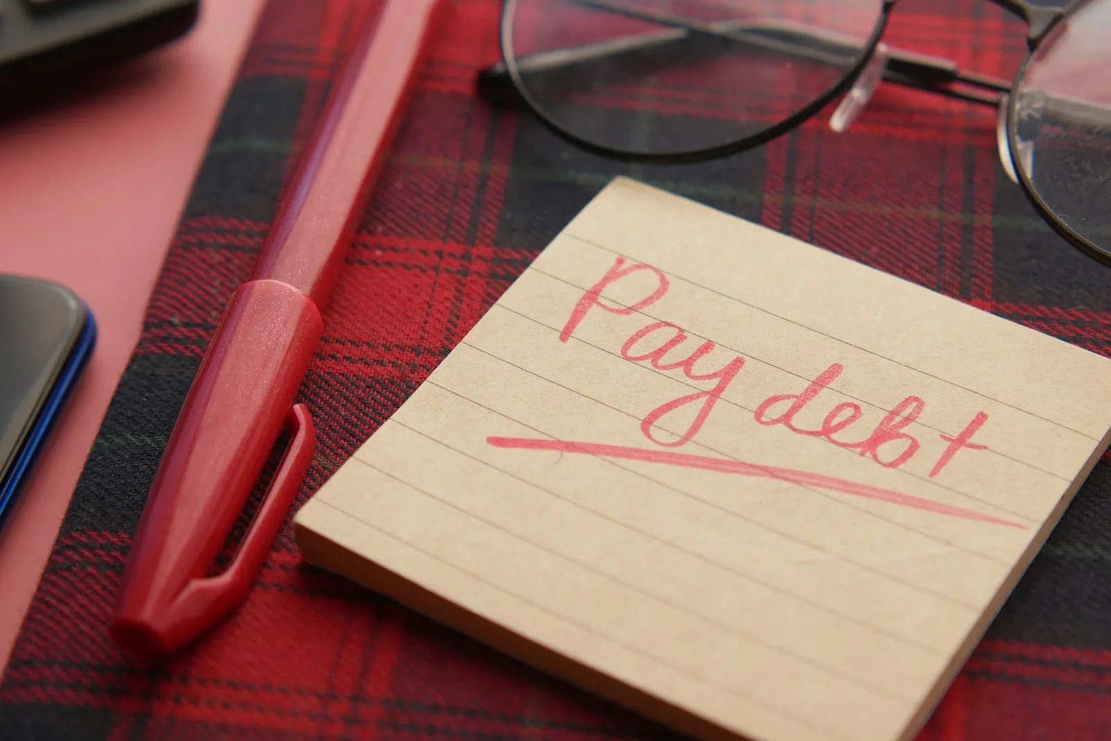 A sticky note stating the word “Pay Debt”