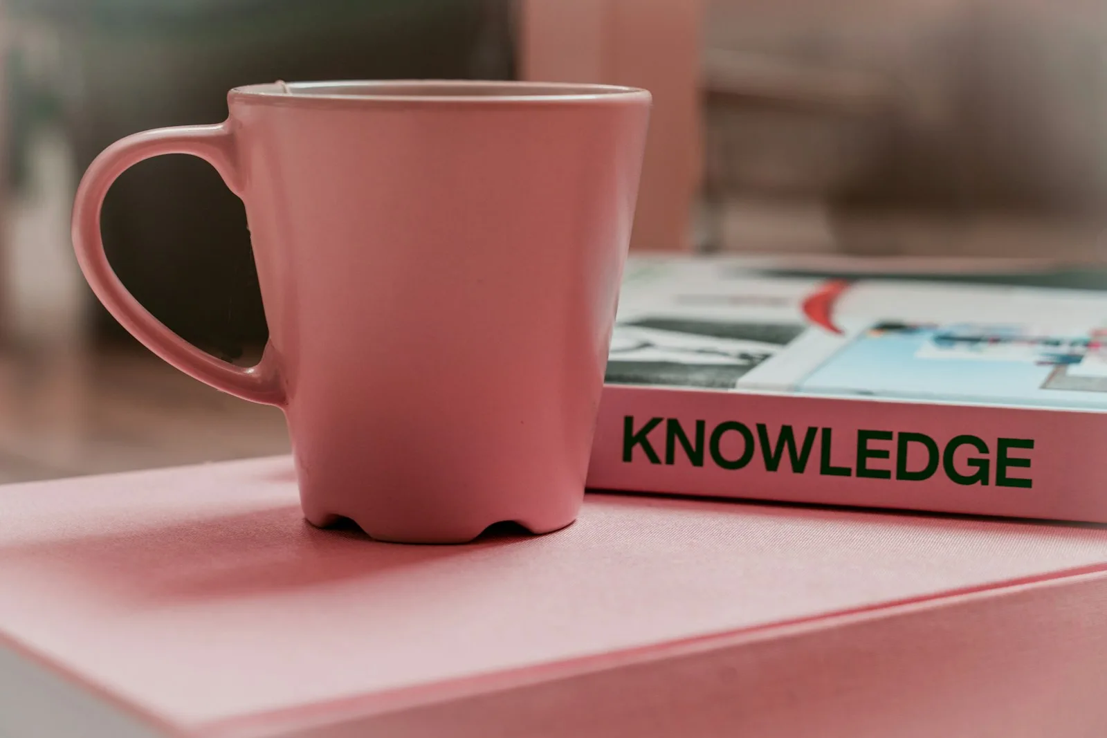 A coffee cup with a book on credit counselling that has the word “Knowledge” written on it’s side.