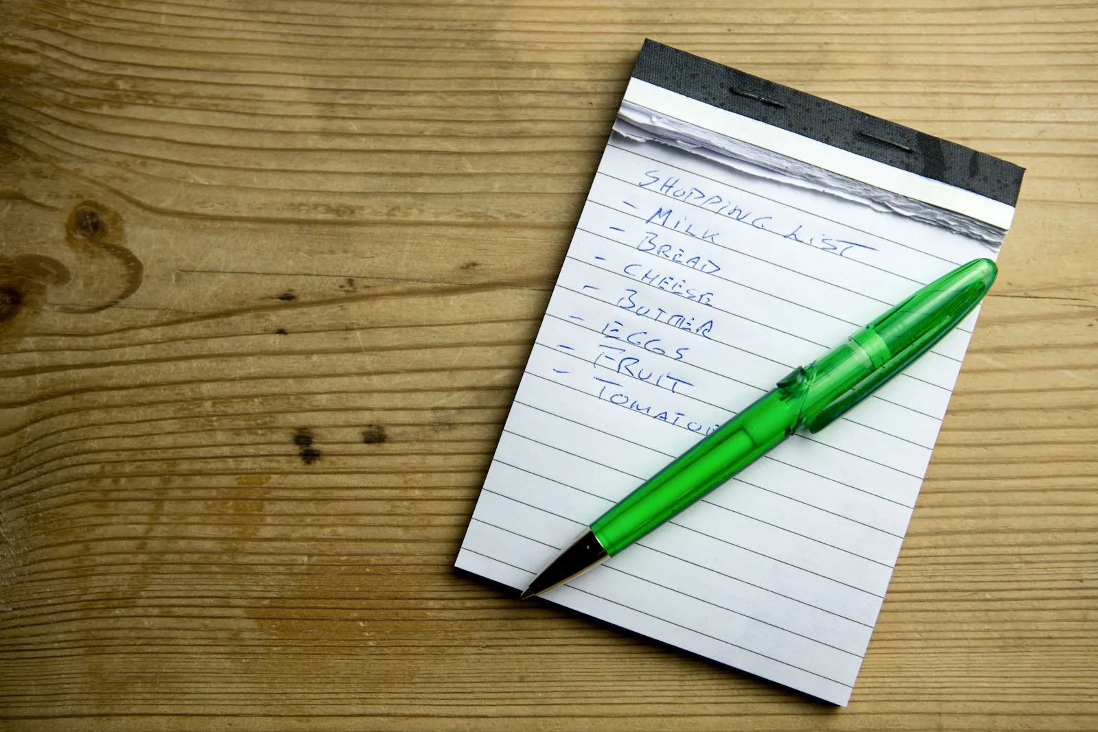 A shopping list on a notepad and a pen
